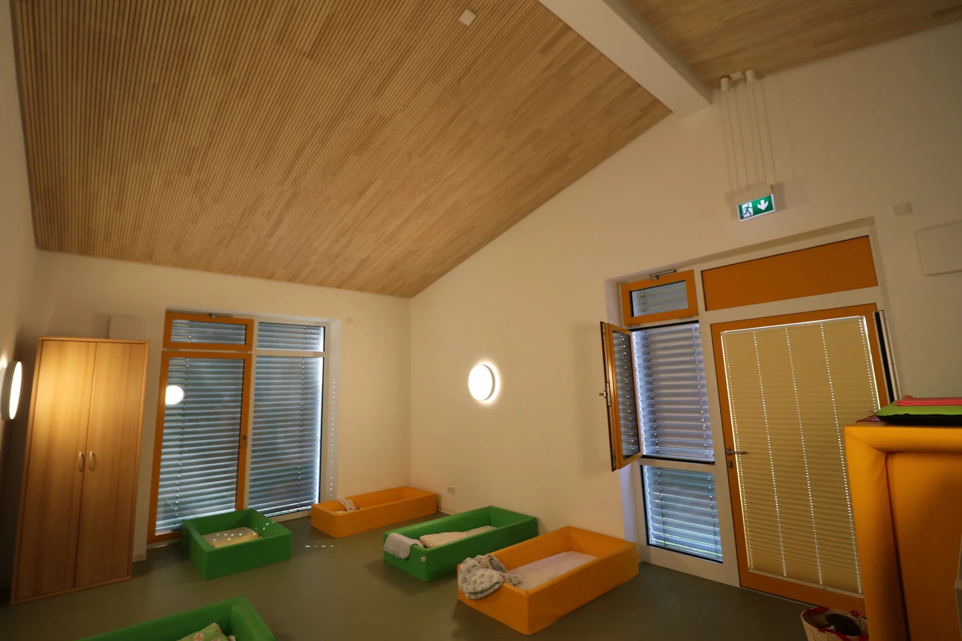 Freundlicher Ruheraum mit runden Innenfenstern und Holzdecke im Familienzentrum Wirbelwind